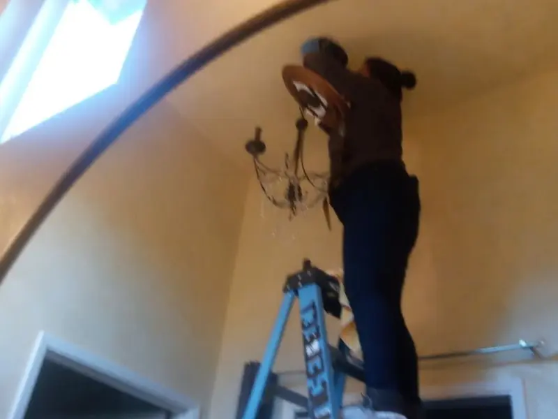Electrician installing a chandelier in a Spanish Lake residence